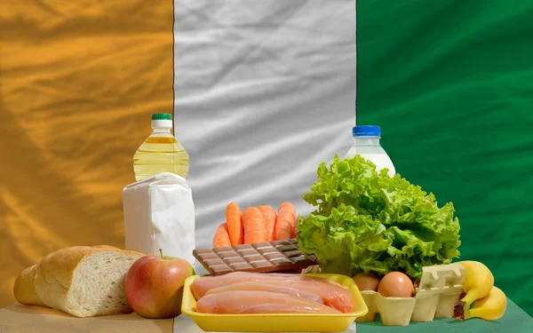 Abarrotes de alimentos básicos frente a la bandera nacional de Costa de Marfil —  Fotos de Stock