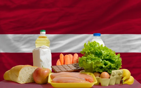 Abarrotes de alimentos básicos frente a la bandera nacional de Latvia — Foto de Stock