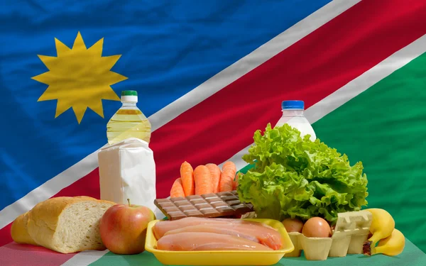 Основные продовольственные товары перед национальным флагом Намибии — стоковое фото
