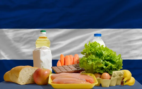 Abarrotes de alimentos básicos frente a bandera nacional de nicaragua — Foto de Stock
