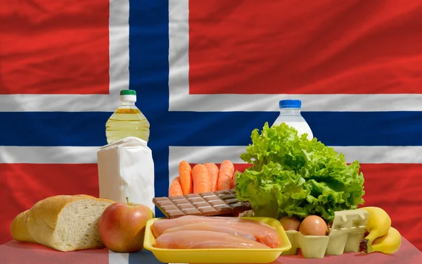 Abarrotes de alimentos básicos frente a la bandera nacional de Noruega — Foto de Stock