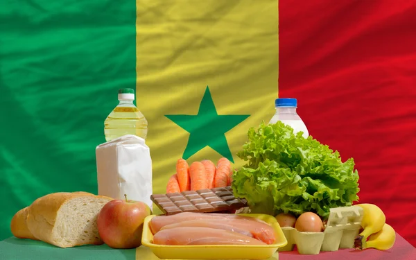 Abarrotes de alimentos básicos frente a la bandera nacional senegal — Foto de Stock