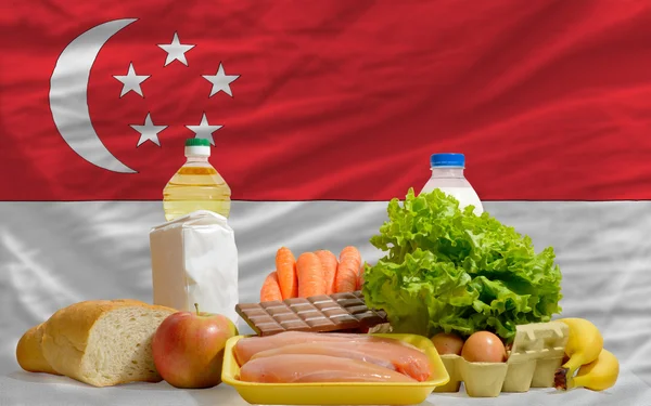 Основные продовольственные товары перед национальным флагом Сингапура — стоковое фото