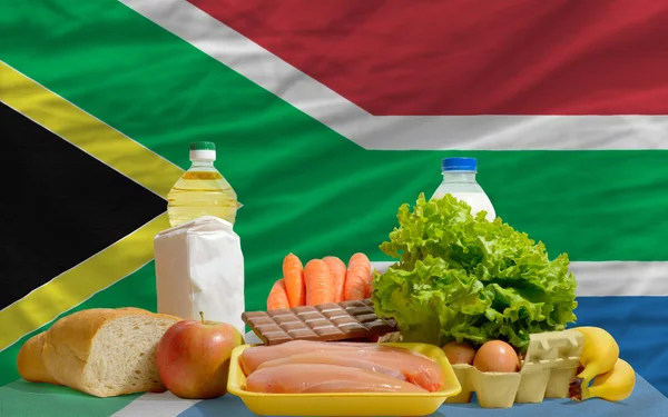 Abarrotes de alimentos básicos frente a la bandera nacional de Sudáfrica —  Fotos de Stock