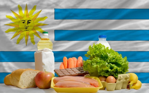 Основные продовольственные товары перед национальным флагом Уругвая — стоковое фото