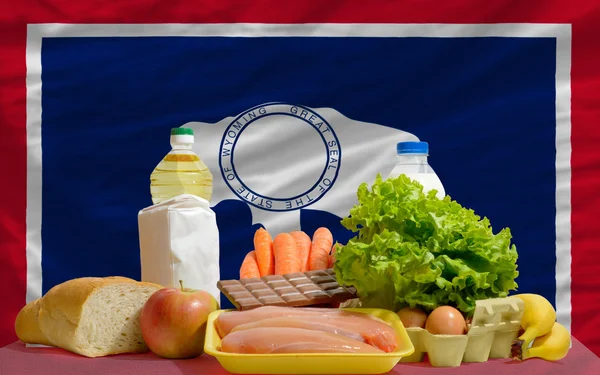 Abarrotes de alimentos básicos frente a la bandera del estado de Wyoming nosotros — Foto de Stock