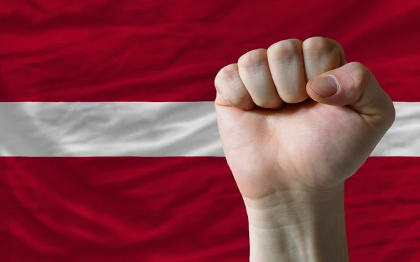 Tvrdá pěst před Lotyšsko vlajku symbolizující sílu — Stock fotografie