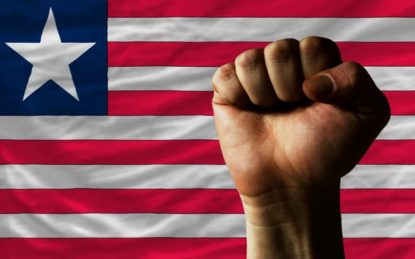 Hard fist in front of liberia flag symbolizing power — Stock Photo, Image