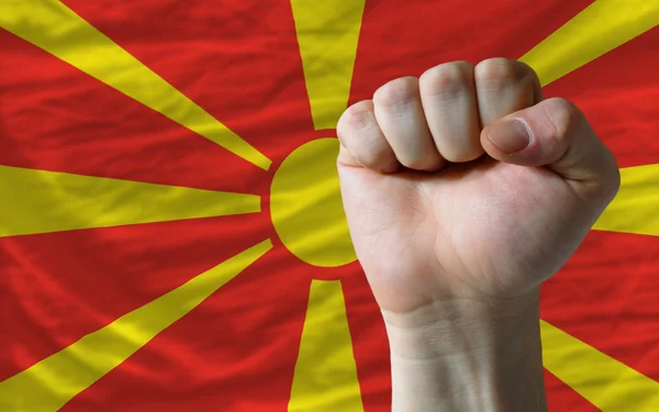 Жесткий кулак перед флагом Мачедонии, символизирующим власть — стоковое фото
