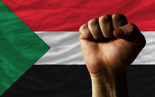 Poing dur devant le drapeau soudan symbolisant le pouvoir — Photo