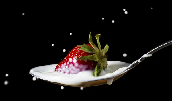 stock image Red, ripe strawberry falling in spoon with milk