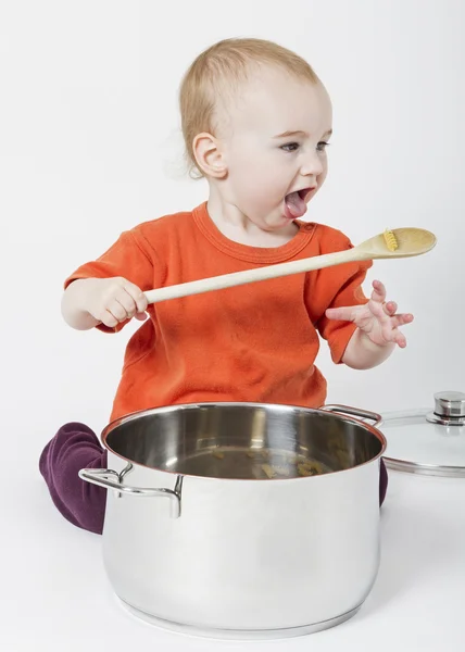 Baby met grote kookpot en houten lepel — Stockfoto