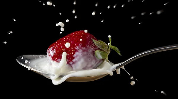 stock image Red, ripe strawberry falling in spoon with milk