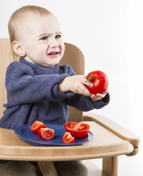Barn äter tomater i barnstol — Stockfoto