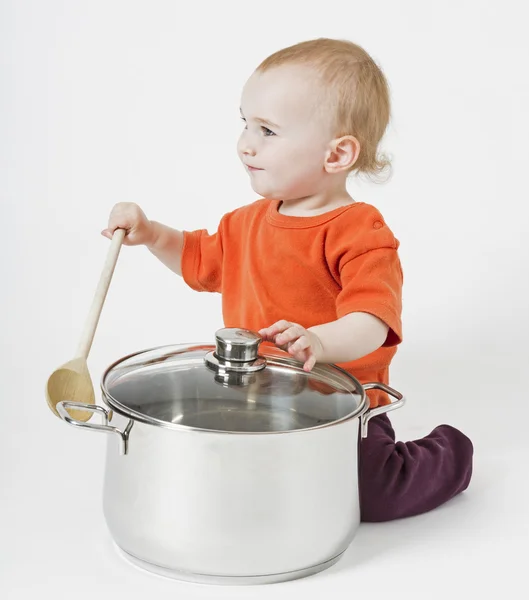 Baby met grote kookpot en houten lepel — Stockfoto