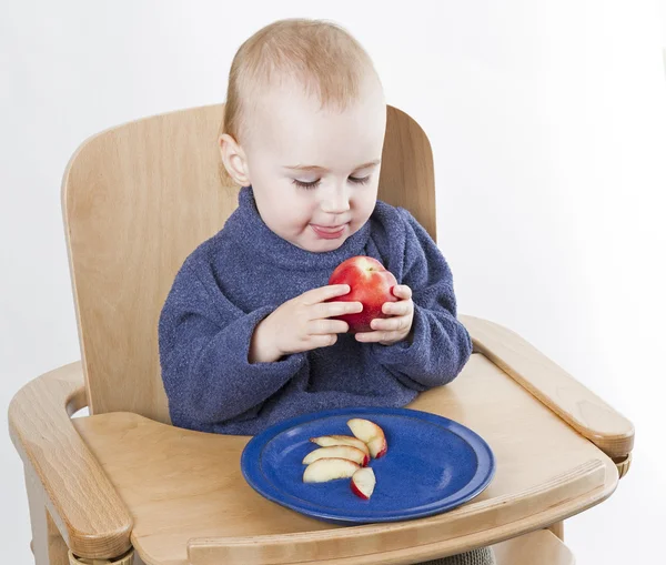 Niño pequeño comiendo melocotones en silla alta — Foto de Stock