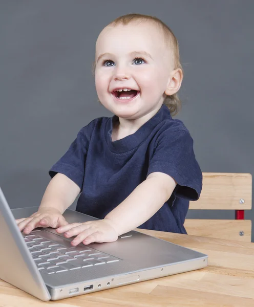 회색 배경에서 노트북 컴퓨터와 아기 — 스톡 사진