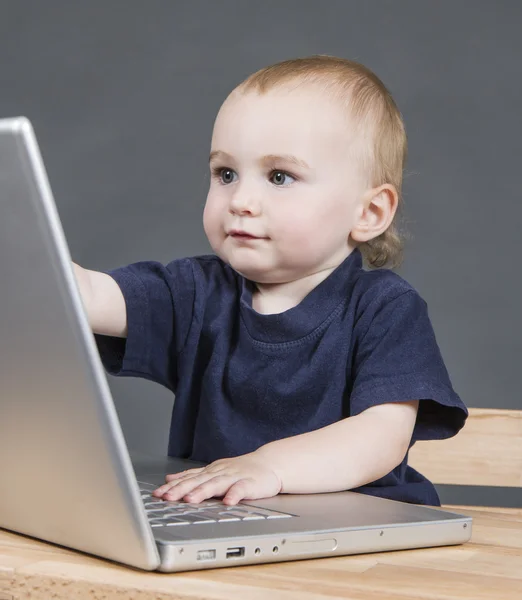 Bébé avec ordinateur portable en fond gris — Photo