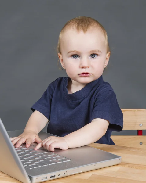 Bambino con computer portatile su sfondo grigio — Foto Stock