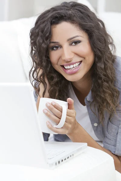 Frau lächelt und trinkt Tee oder Kaffee mit Laptop — Stockfoto