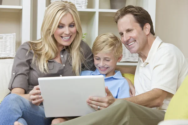 Dizüstü bilgisayar kullanan koltukta oturan mutlu bir aile — Stok fotoğraf