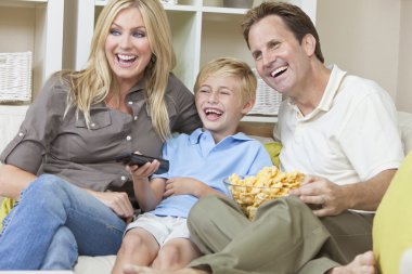 Happy Family Sitting on Sofa Laughing Watching Television clipart