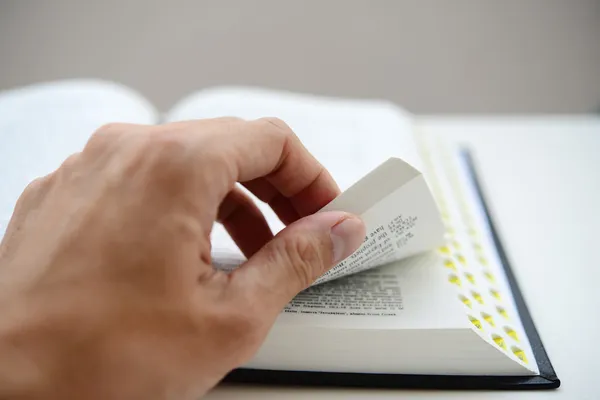 Hand blättert die Bibelseiten mit seichtem Dof — Stockfoto