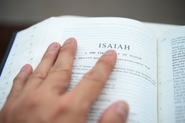 Hand flipping the bible on isaiah page with shallow DOF clipart
