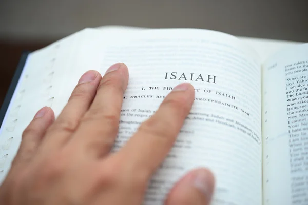 Mão lançando a bíblia na página de Isaías com DOF rasa — Fotografia de Stock