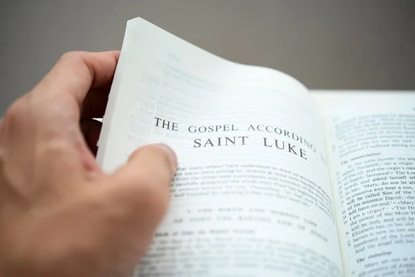 Hand flipping the Gospel of St Luke with shallow DOF — Stock Photo, Image