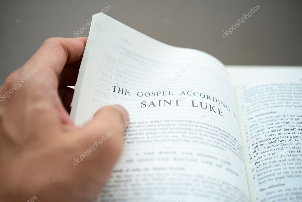 Hand flipping the Gospel of St Luke with shallow DOF