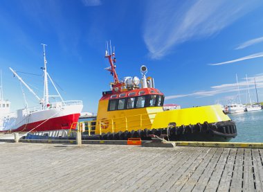 Bright yellow tug boat in the harbor clipart