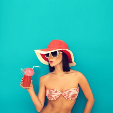 Güneş gözlüklü şehvetli kadın kokteyl içiyor.