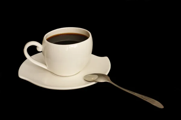 Eine schöne Kaffeetasse mit Untertasse und Löffel auf schwarzem Hintergrund — Stockfoto