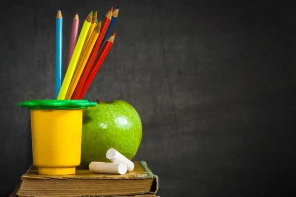 彩色铅笔、 粉笔和老书上的绿色苹果 — 图库照片
