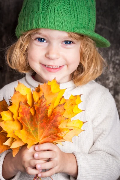Criança sorridente feliz segurando folhas de bordo amarelas — Fotografia de Stock