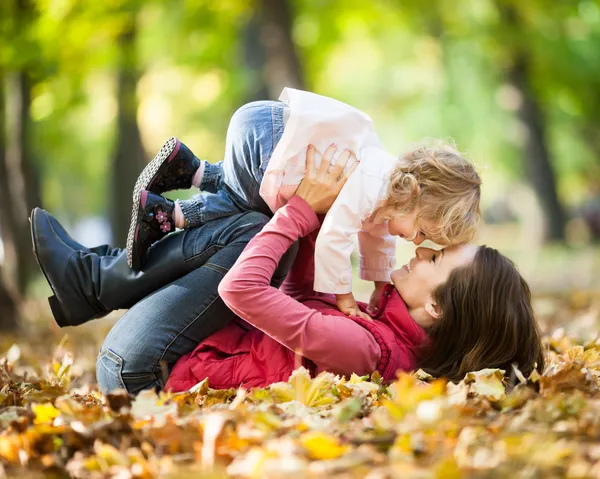 Mulher com criança se divertindo no parque de outono — Fotografia de Stock
