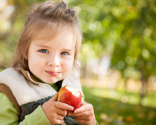 Criança com maçã no parque de outono — Fotografia de Stock