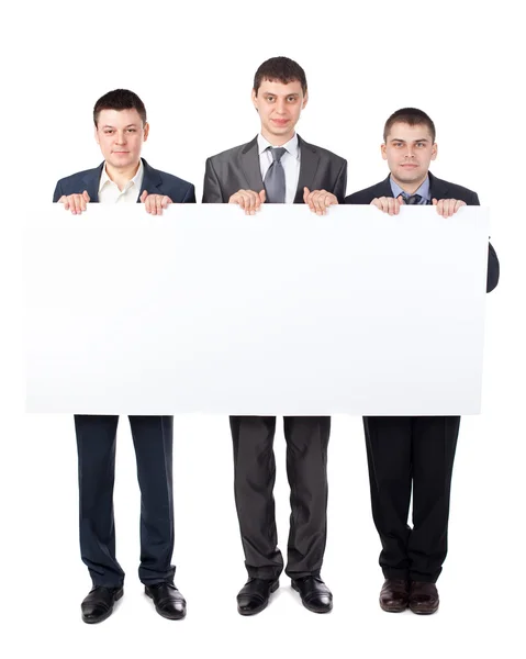Three young businessmen hold up a large blank sign isolated on w — Stock Photo, Image