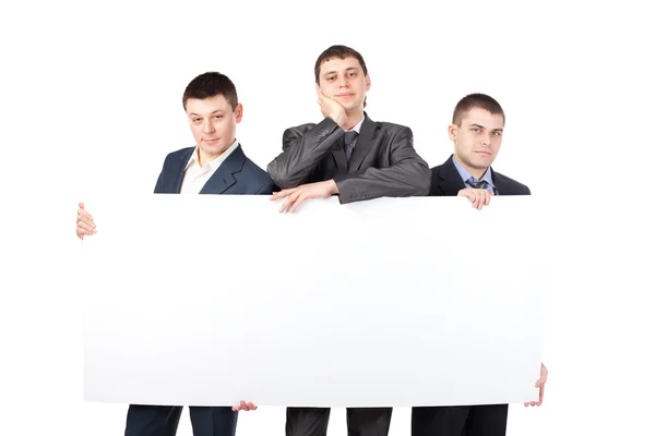 Three young businessmen hold up a large blank sign isolated on w — Stock Photo, Image