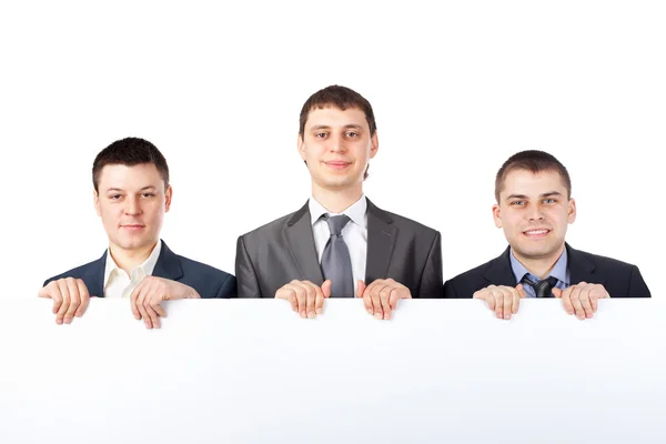 Három fiatal üzletember ragaszkodik egy nagy üres jel elszigetelt w — Stock Fotó