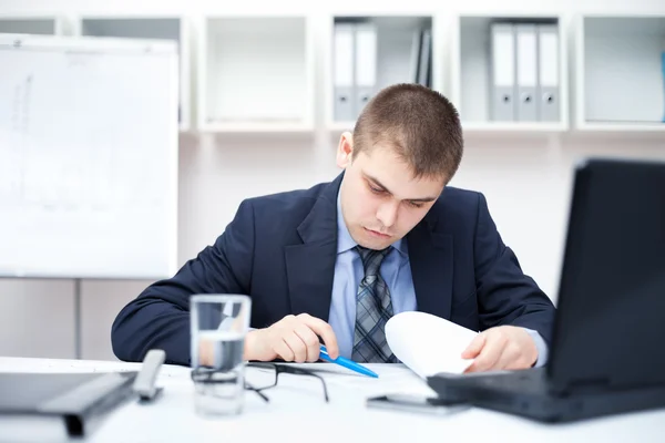 Porträt eines jungen Geschäftsmannes im Büro, der Papierkram erledigt — Stockfoto