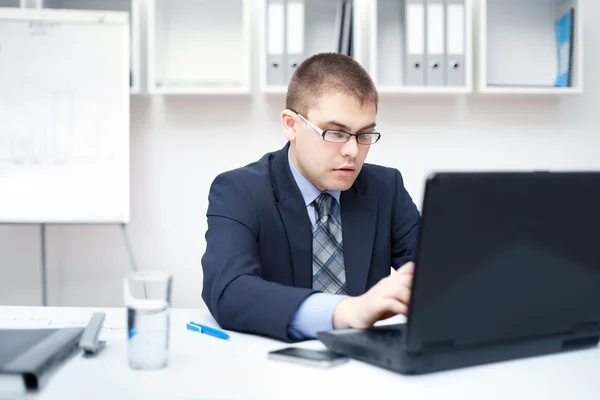 Retrato del joven hombre de negocios que trabaja en una computadora portátil en la oficina — Foto de Stock
