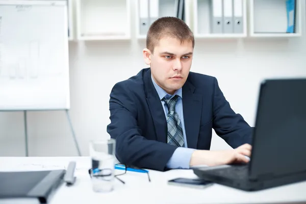 Jovem empresário trabalhando no laptop no escritório — Fotografia de Stock