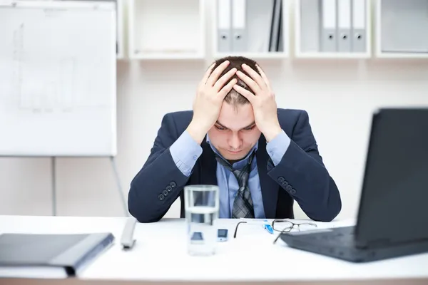 Deprimido jovem homem de negócios segurando a cabeça no escritório — Fotografia de Stock