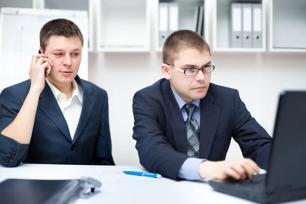 Dos jóvenes empresarios que trabajan junto con el ordenador portátil en la oficina des — Foto de Stock