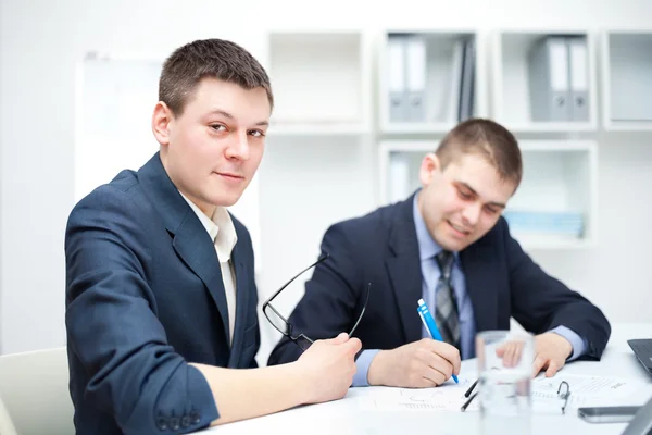 Zwei junge Geschäftsleute unterzeichnen Verträge im Amt — Stockfoto