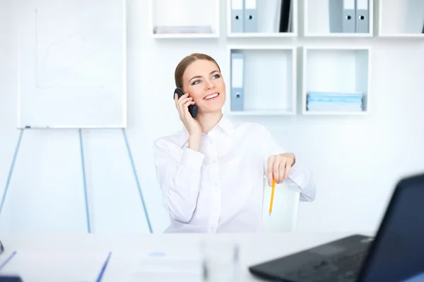 Schöne junge Geschäftsfrau sitzt am Schreibtisch und plaudert — Stockfoto