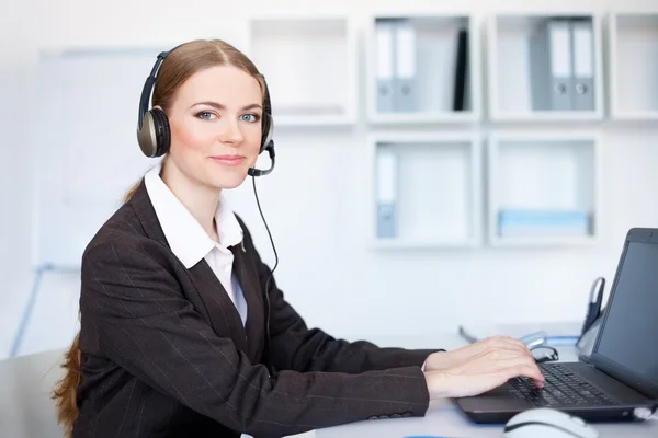 Portrait of pretty young female operator sitting at office desk — Stock Photo, Image