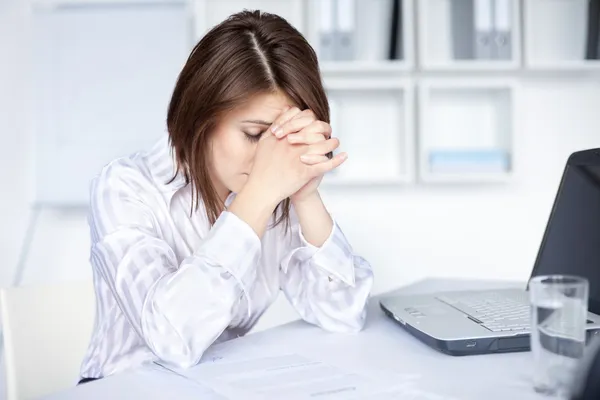 Trøtt, ung forretningskvinne på lysende kontor stockfoto